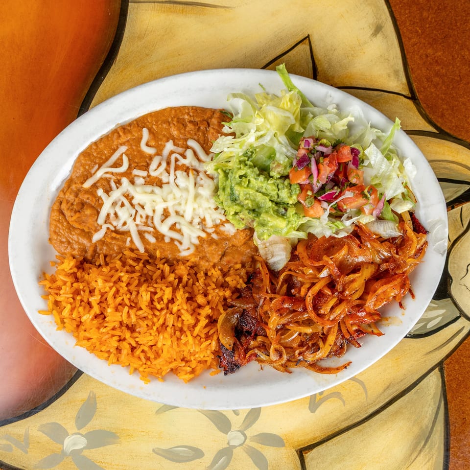 Mexican plate with refried beans, melted cheese, rice, grilled onions, guacamole, pico de gallo, and lettuce salad.